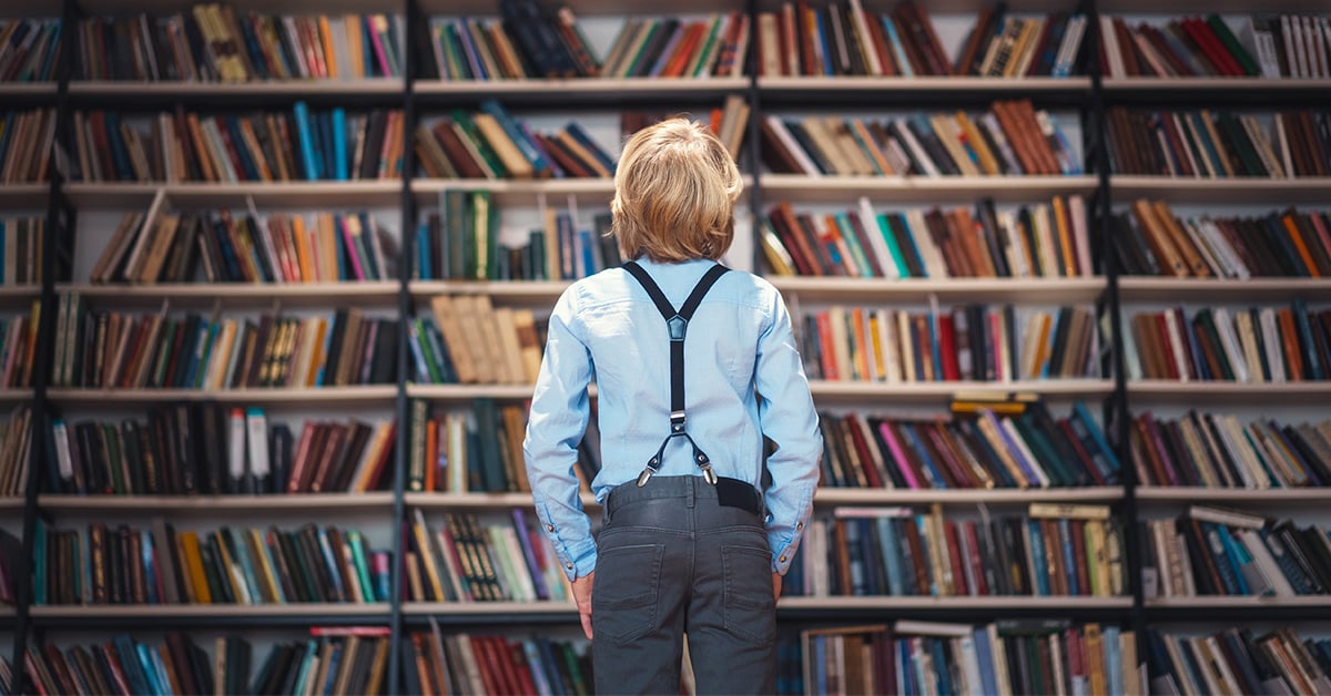 Boy looking at library shelves with books